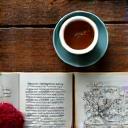 Primo piano di una tazza di tè caldo con erbe aromatiche e un libro, simbolo di relax serale.